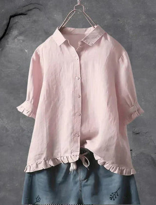 Light pink button-up blouse top with collar, short sleeves, and ruffled hem detail
