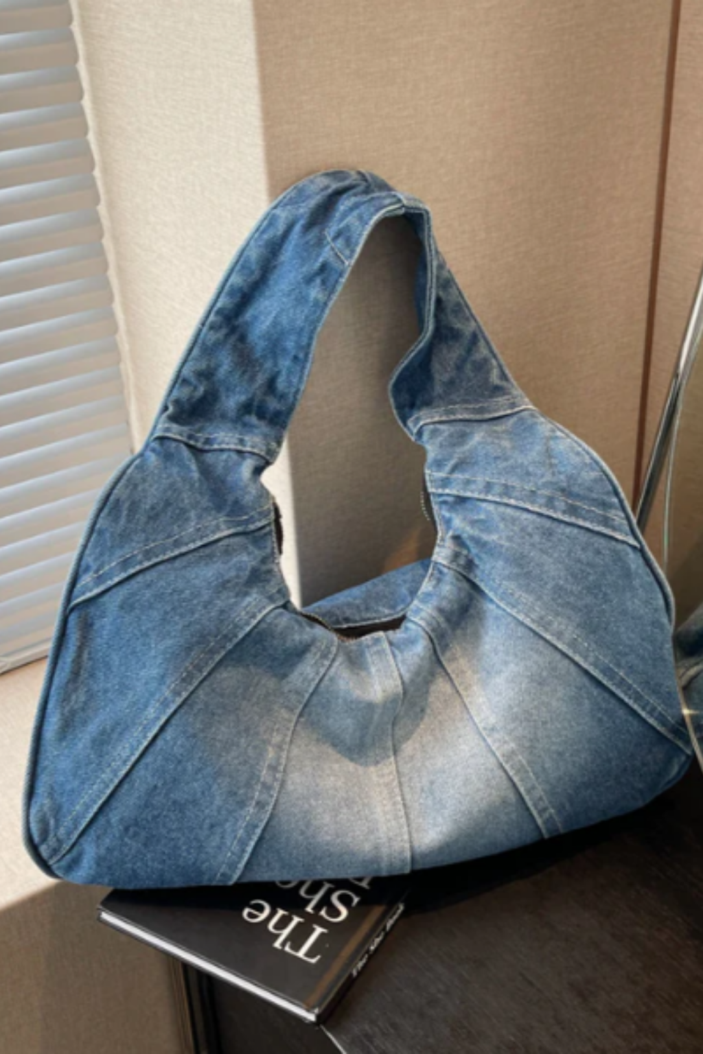 Denim shoulder bag in light blue with wide top handles and curved, open top
