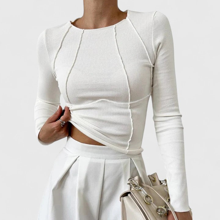White long-sleeve knit top with cropped asymmetric hem and twisted front seams.