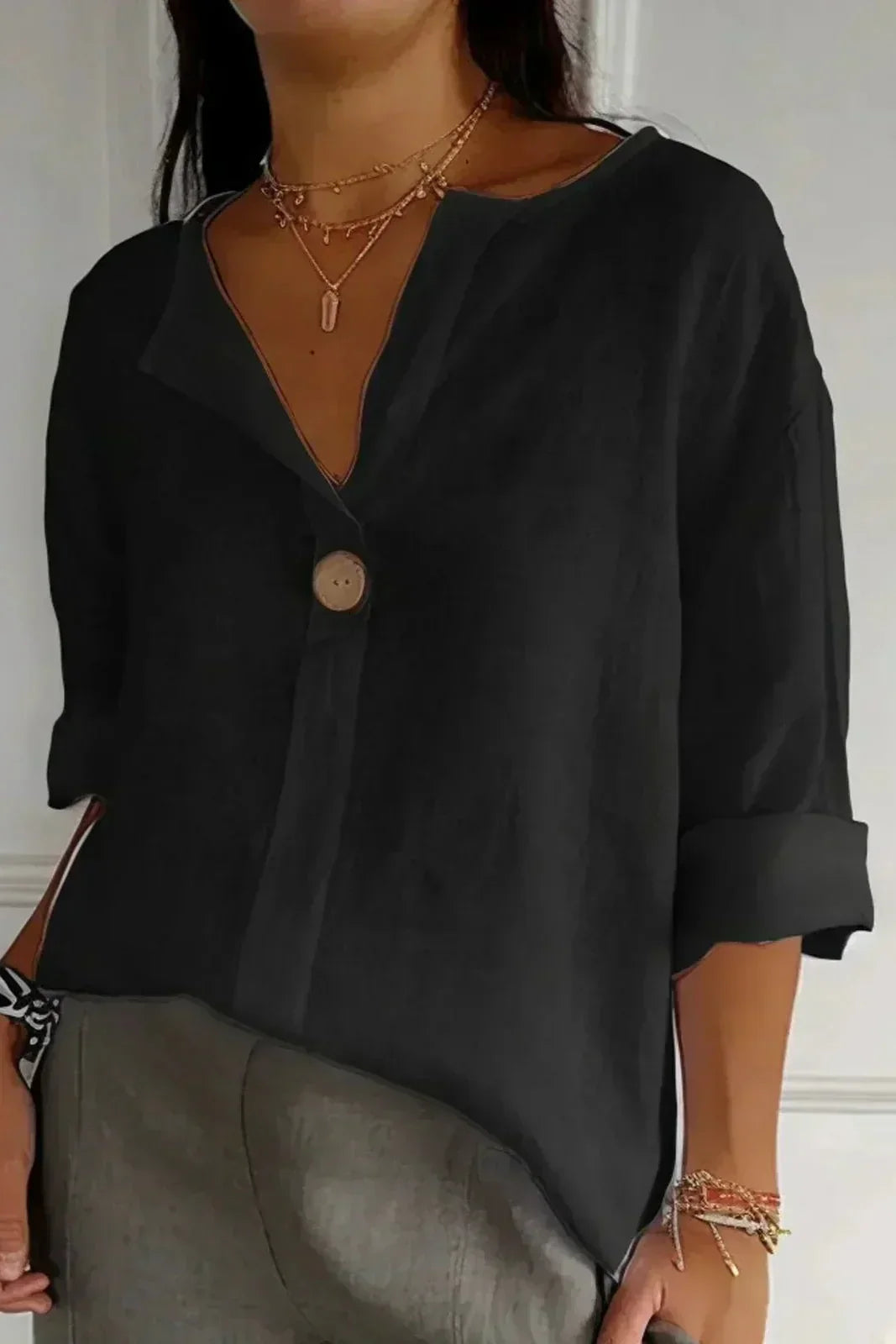 Relaxed black button-up top with V-neck and short cuffed sleeves, front button placket.