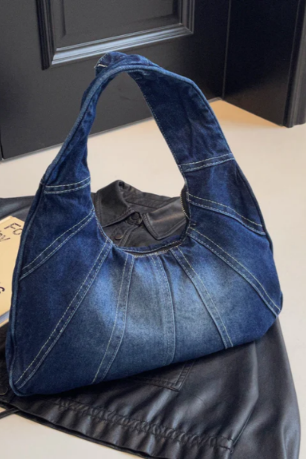 Denim shoulder bag in dark blue with wide top handles and panel stitching