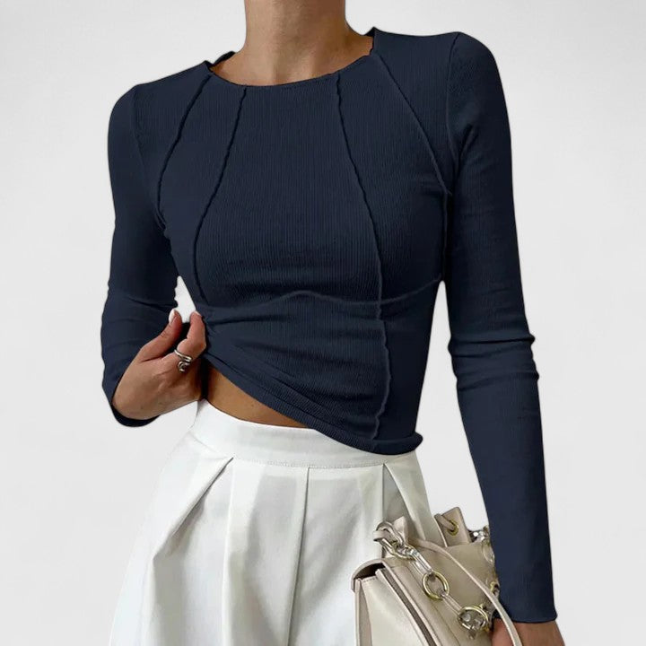 Navy long-sleeve knit top with cropped asymmetric hem and twisted front seams.