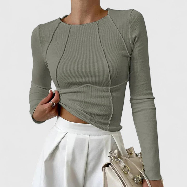 Olive green long-sleeve knit top with cropped asymmetric hem and twisted front seams.