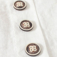 Close-up of three round dark buttons on a white fabric placket