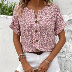 Pink floral print blouse with V-neck and centered gold buttons, short cuffed sleeves