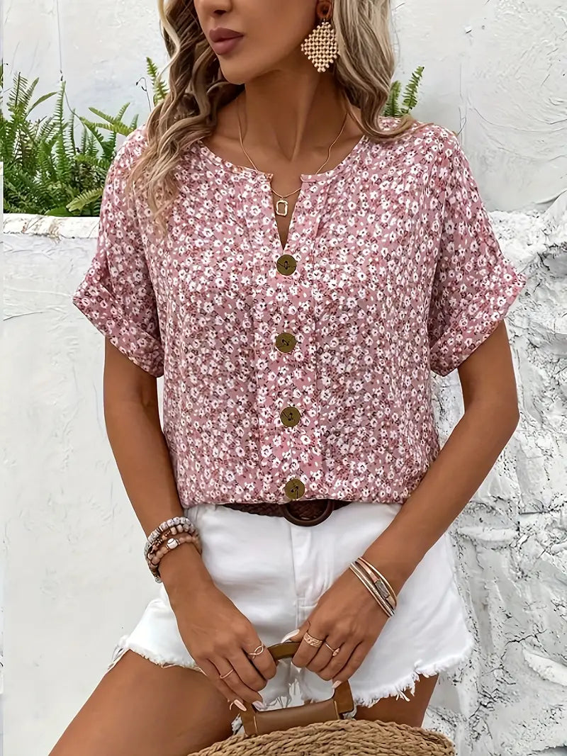 Pink floral print blouse with V-neck and centered gold buttons, short cuffed sleeves