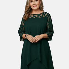 Green dress with sheer patterned sleeves, geometric yoke, and asymmetric draped hem