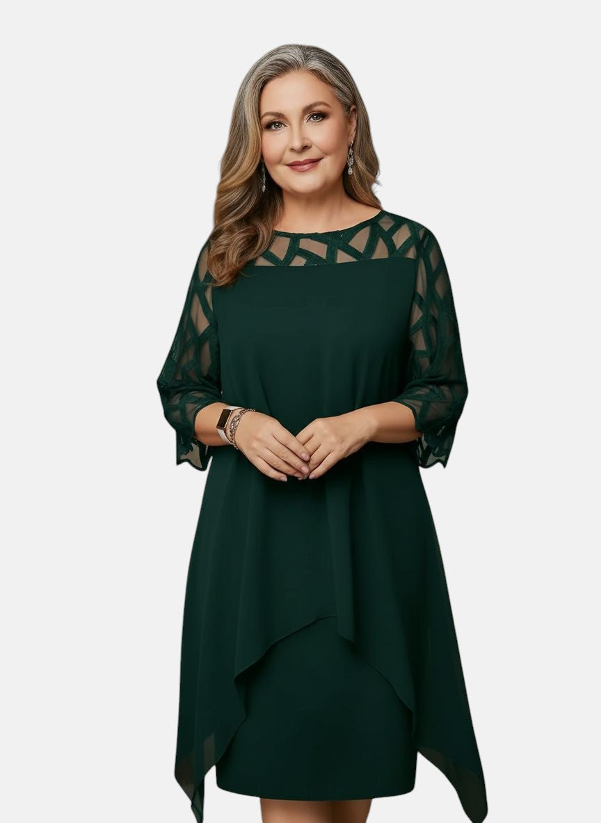 Green dress with sheer patterned sleeves, geometric yoke, and asymmetric draped hem