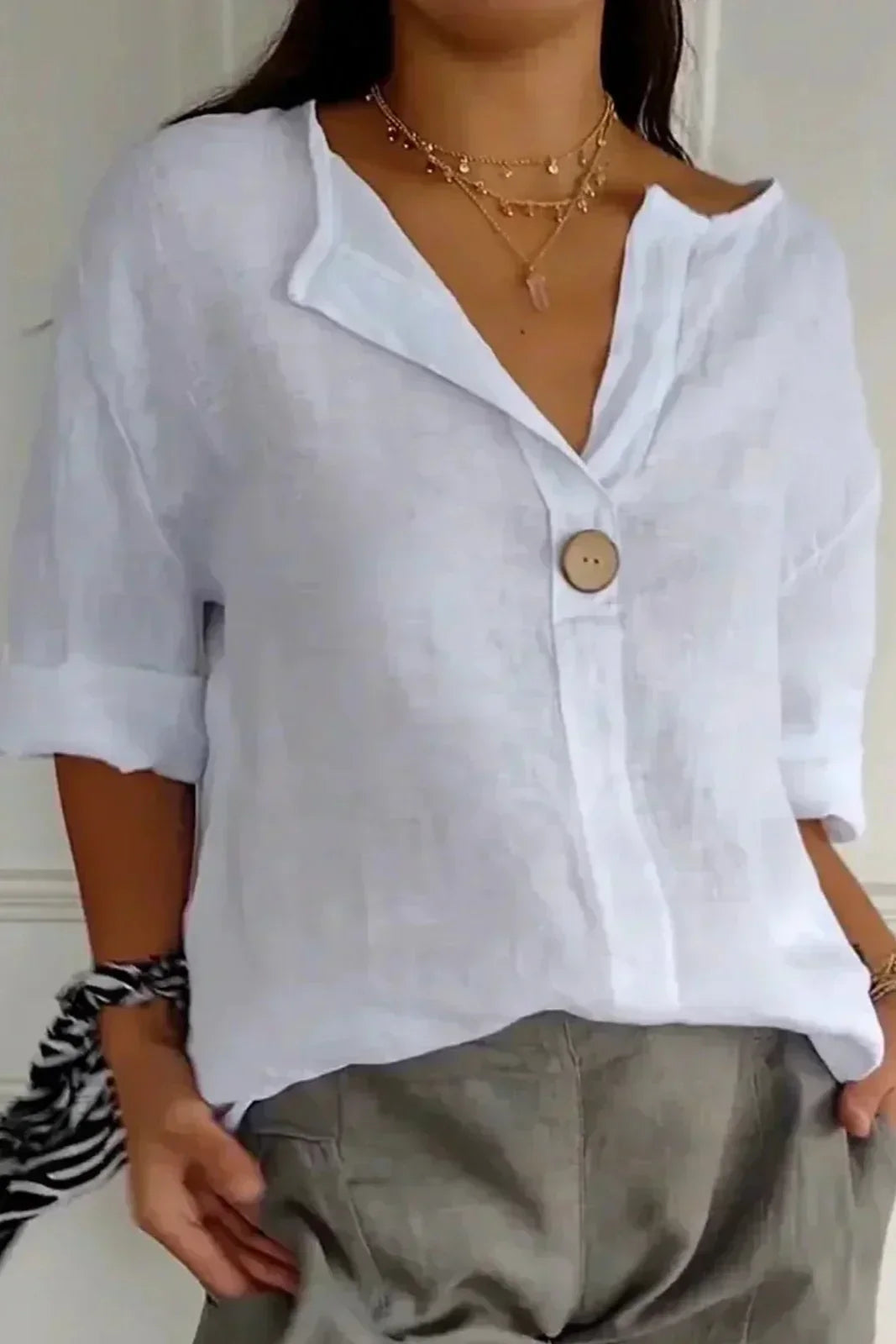 Relaxed white button-up top with V-neck and short sleeves, front button placket.