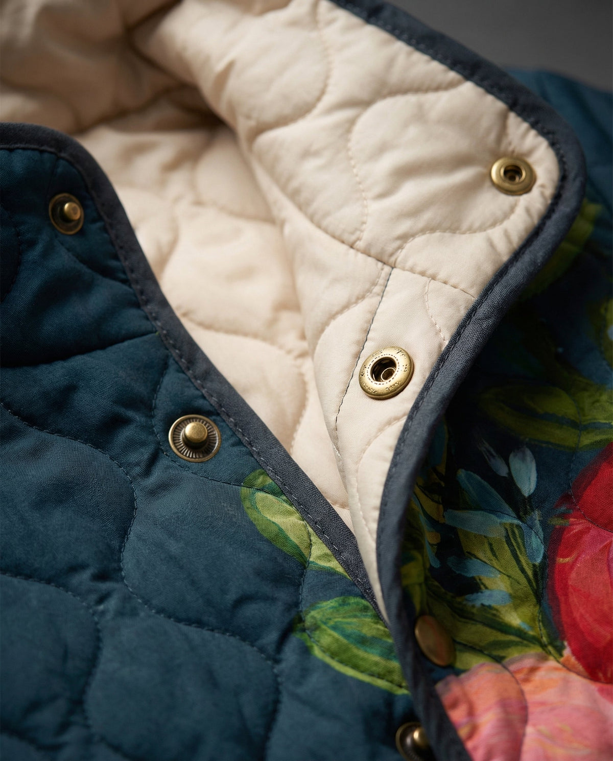 Quilted jacket detail with gold buttons, cream lining, and floral trim