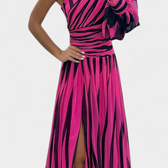 Striped one-shoulder maxi dress in fuchsia and dark tones, fitted bodice, side slit.