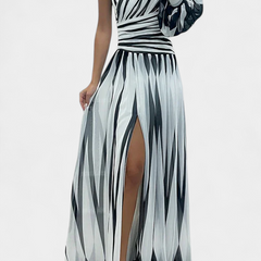 One-shoulder striped maxi dress in light and dark tones, draped bodice, side slit.