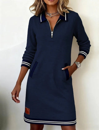 Dark navy long-sleeve cotton dress with half-zip collar, side pockets, and striped hem