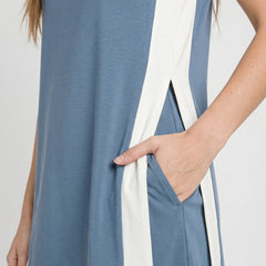 Blue tunic dress detail with white side panels, pocket opening, and curved hem trim