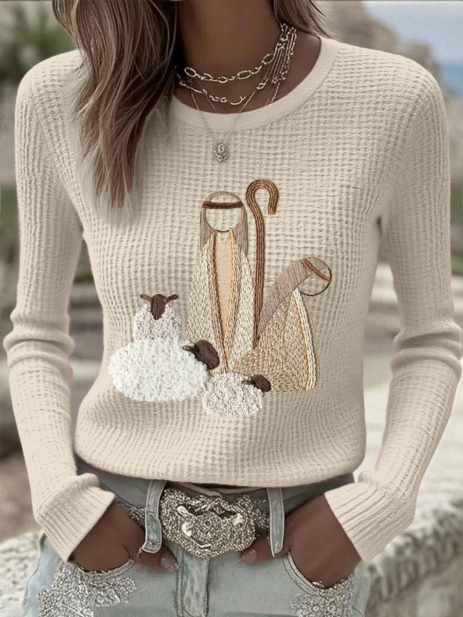 Beige knit long-sleeve top with nativity scene applique graphic at chest
